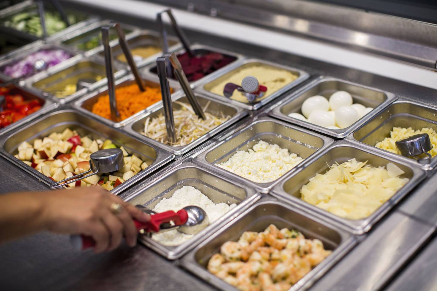 Un trabajador escoge un ingrediente para un pedido de la barra de ensaladas dentro de un restaurante de Sweetgreen Inc. en Boston.