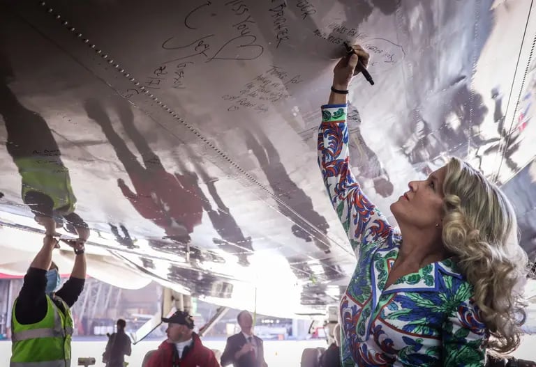 Qantas built its long-haul ambitions around the 747, connecting Australia to the rest of the world with the jumbo painted in a distinct kangaroo livery. Here, cabin crew and ground staff sign the underneath of the fuselage of a Boeing 747-400 in 2020 before it takes off at Sydney Airport for the last time before it retired from service. Photographer: David Gray/Getty Imagesdfd