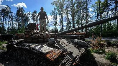 Un hombre inspecciona un tanque ruso destruido en el pueblo de Dmytrivka, cerca de Kyiv, Ucrania.