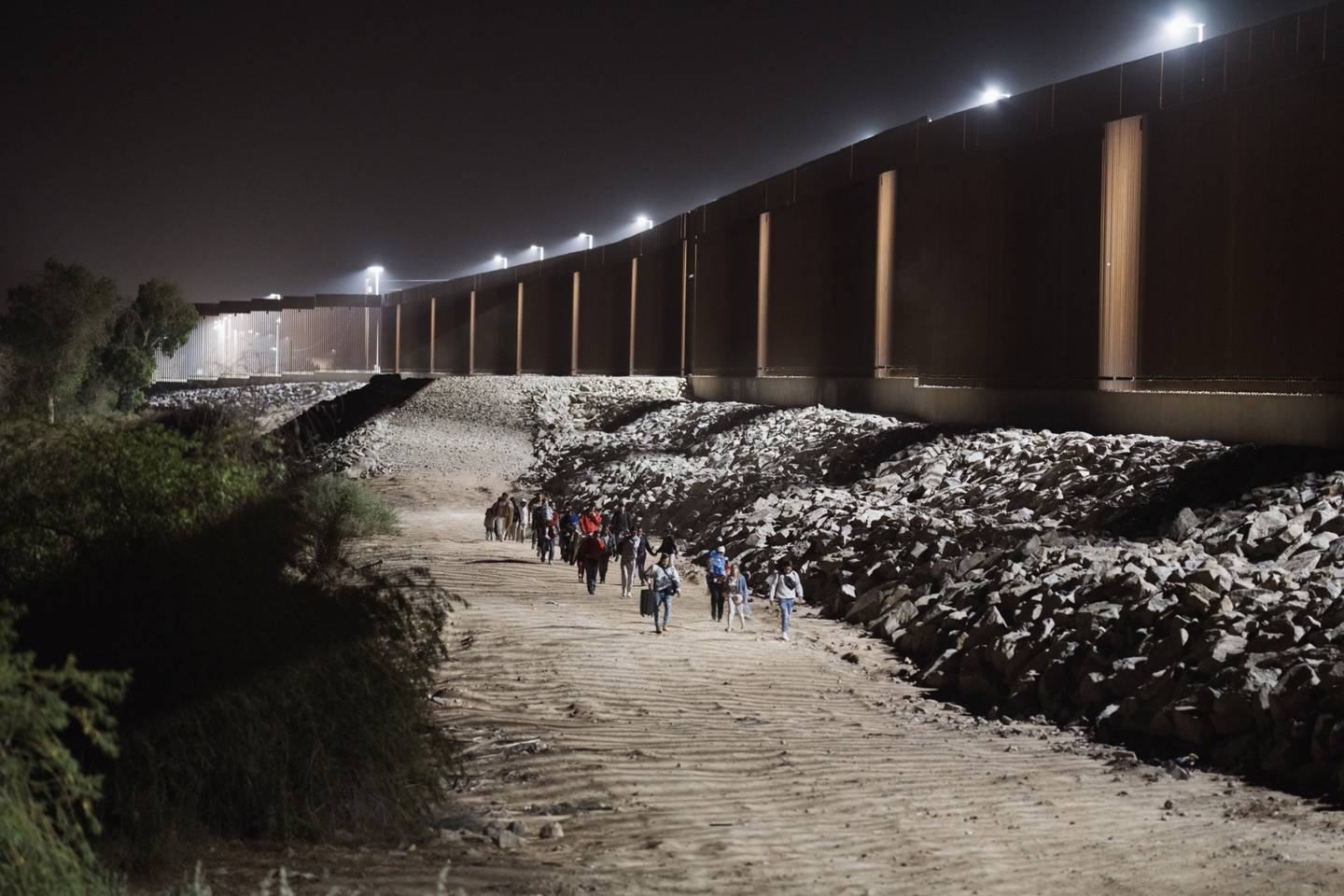 Migrants walks along the border fence before surrendering to US Border Patrol agents, in Yuma, Arizona, US, on May 10.