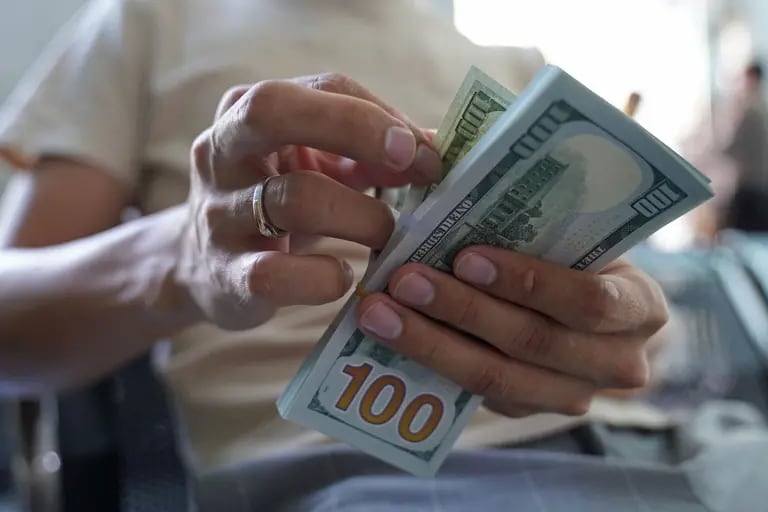 Un hombre cuenta billetes de dólares estadounidenses en una oficina de cambio el miércoles 2 de marzo de 2022.dfd