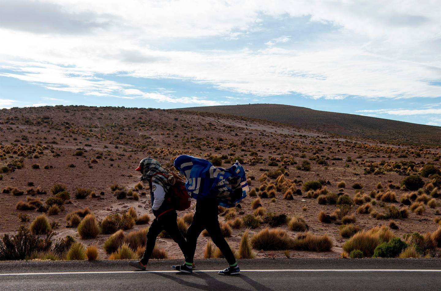 Migrantes venezolanos caminan por la carretera que une Iquique con Colchane, luego de cruzar de Bolivia a Chile, en Quebe, Chile, el 17 de febrero de 2021.Fotógrafo: Martin Bernetti / AFP / Getty Images