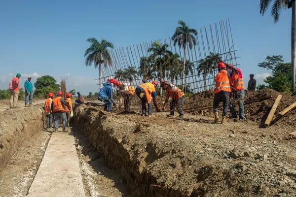 Workers build a border wall to stop the flow of migrants fleeing Haiti.
