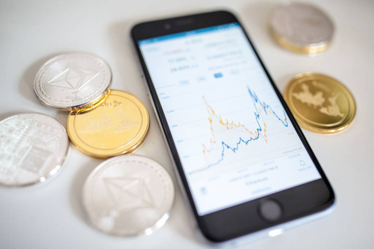 Criptomonedas litecoin, ripple y ethereum 'altcoins' (monedas alternativas) junto a un teléfono inteligente que muestra el gráfico de precios actual.