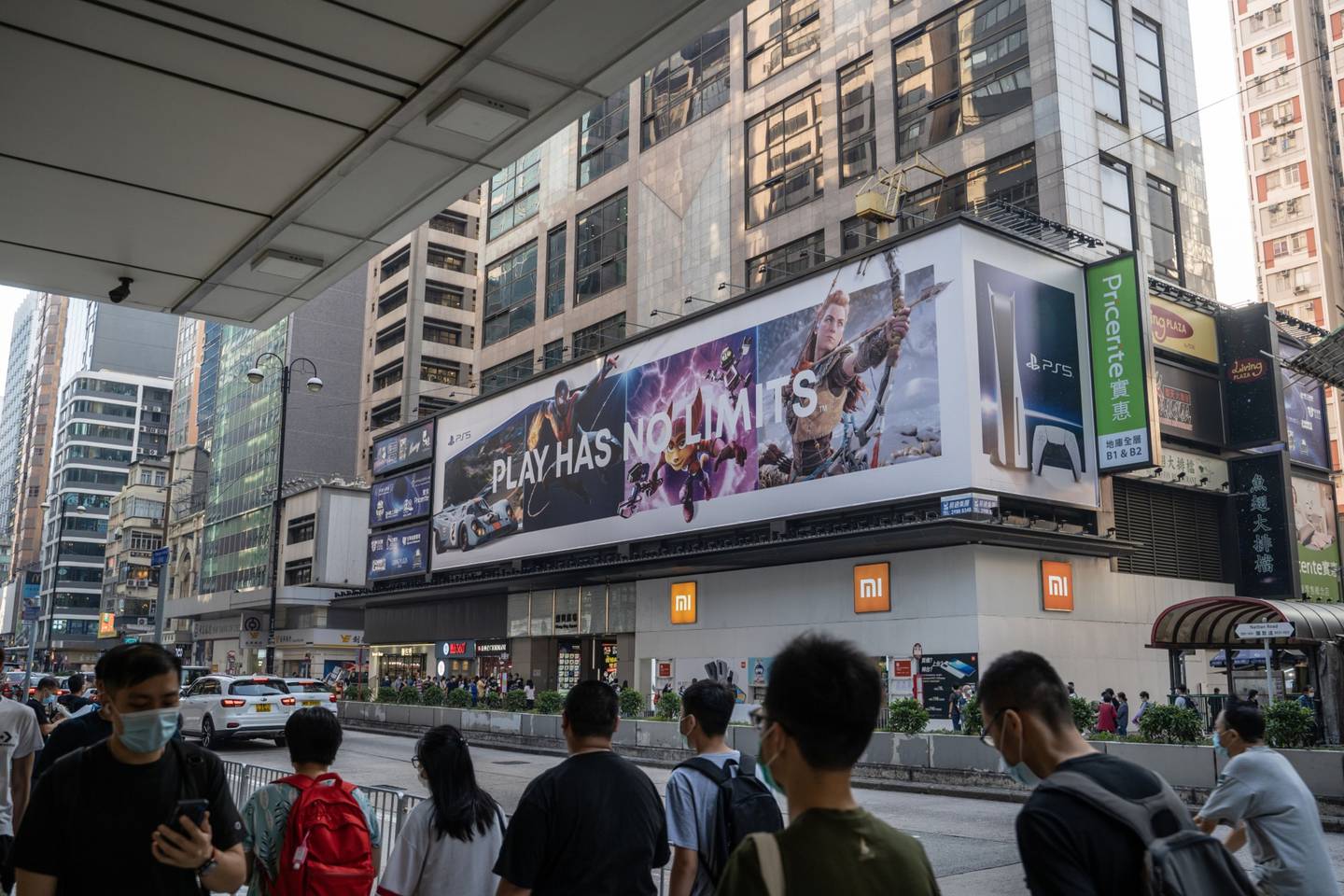 Pedestrians wearing protective mask walk past a billboard advertising the Sony Corp. PlayStation 5 game console in Hong Kong, China, on Thursday, Nov. 26, 2020. The newest video-game console from Sony Corp., alongside rival Microsoft Corp.'s updated Xbox, are arguably the hottest items this Black Friday as shoppers line up in person or swarm retailers' websites hoping to snag one. Photographer: Roy Liu/Bloomberg