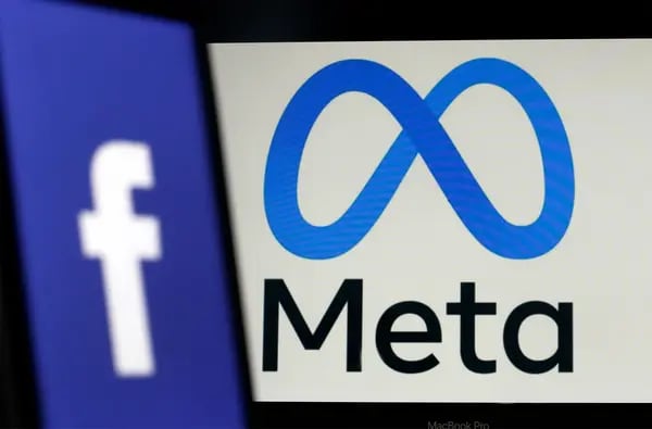 Logo de Facebook se muestra en la pantalla de un iPhone delante de un logo de Meta