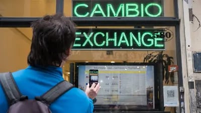 A pedestrian uses a mobile device to take a photograph of a sign displaying exchange rates outside of a currency exchange house in Buenos Aires, Argentina, on Thursday, Aug. 30, 2018. Argentina's currency crisis intensified on Thursday as the peso plunged 20 percent in a rout that only accelerated after the central bank tried to shore up confidence with an emergency increase in interest rates. Photographer: Erica Canepa/Bloomberg