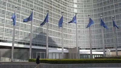 Un peatón pasa junto a los mástiles mientras las banderas de la Unión Europea (UE) ondean frente al edificio de la Comisión Europea en Bruselas, Bélgica. Fotógrafo: Jasper Juinen/Bloomberg