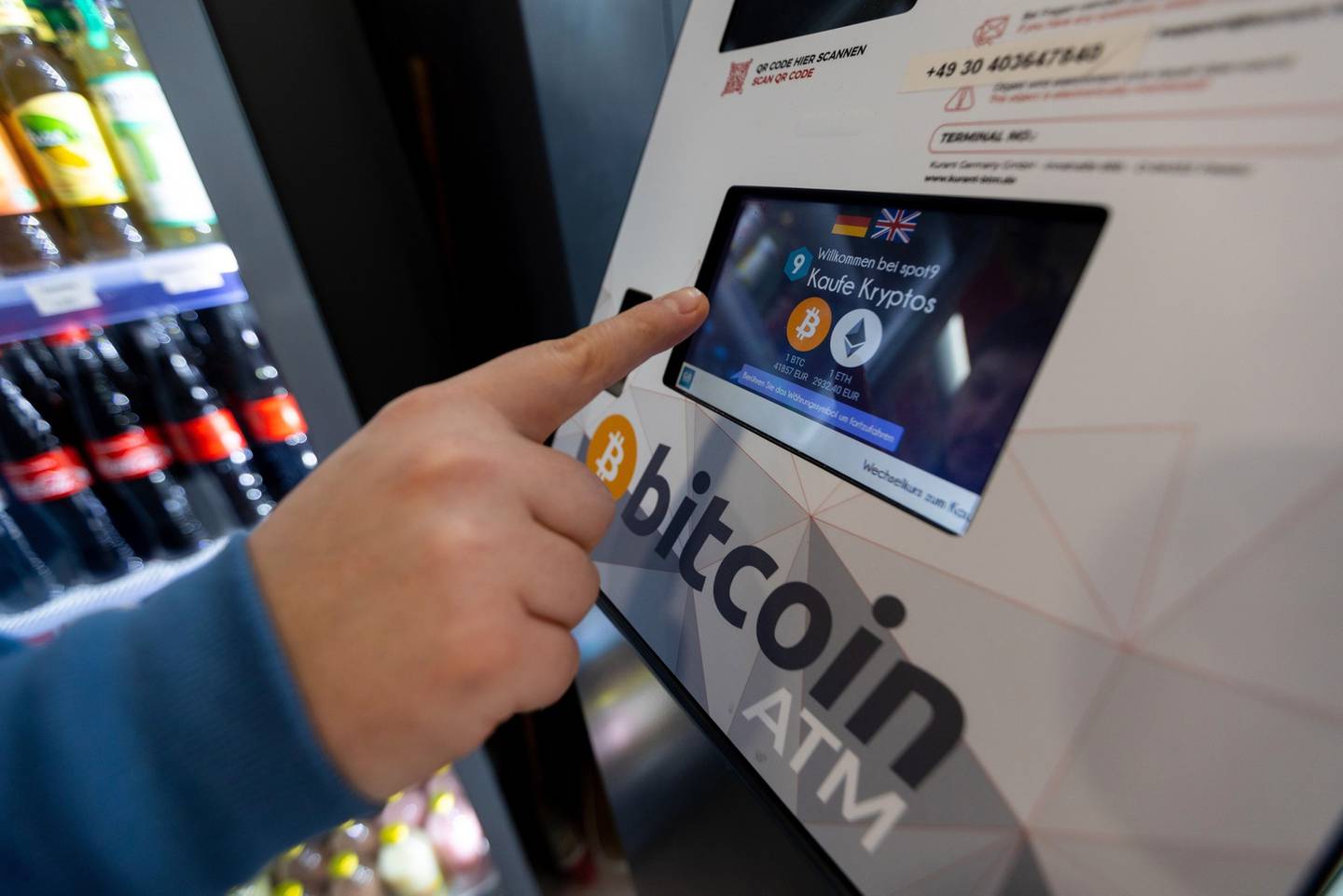 Un cajero automático (ATM) de Bitcoin en uso, dispuesto dentro de una tienda.