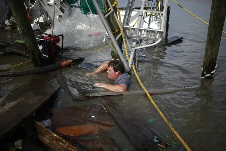Una persona trabaja para salvar un barco de pesca que quedó parcialmente sumergido por el huracán Ida en Golden Meadow, Luisiana.dfd