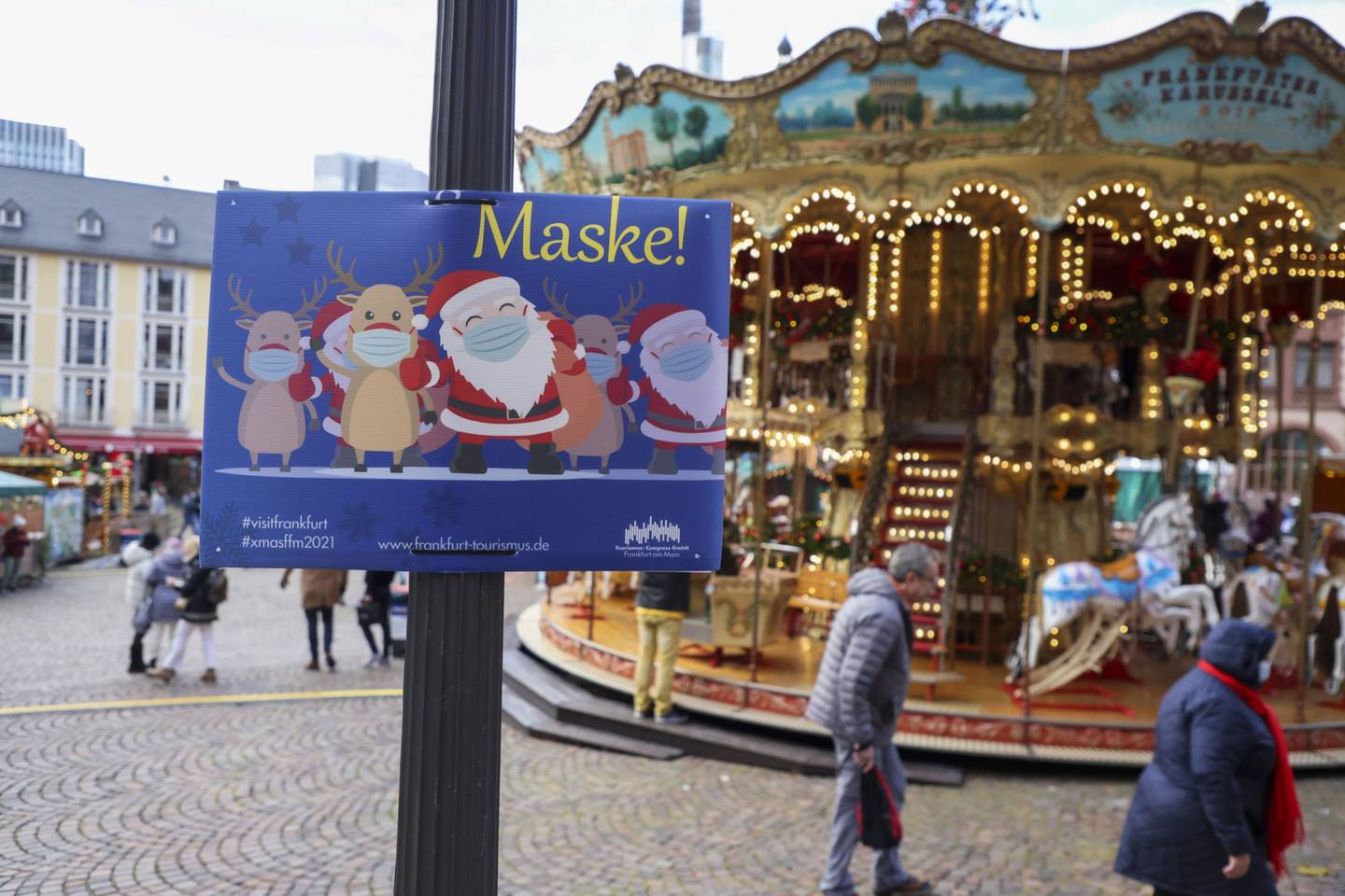 Un cartel recuerda a los visitantes que deben llevar mascarillas mientras visitan un mercado navideño en Fráncfort, Alemania, el lunes 22 de noviembre de 2021.