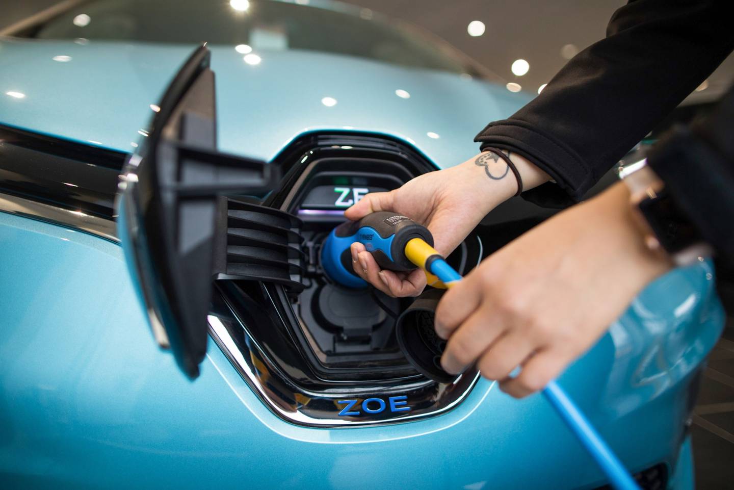 Un empleado coloca el cargador eléctrico en un nuevo automóvil Renault Zoe.