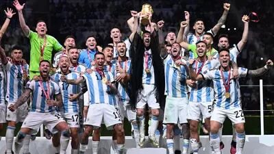 Argentina's captain and forward #10 Lionel Messi (C) lifts the FIFA World Cup Trophy as he celebrate with teammates winning the Qatar 2022 World Cup final football match between Argentina and France at Lusail Stadium.