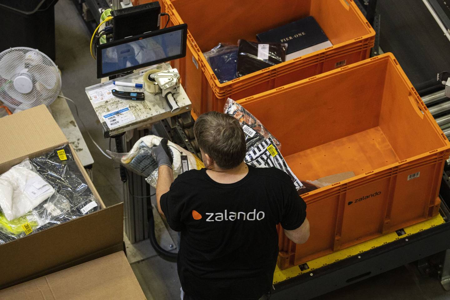 Um funcionário coloca pacotes de roupas selados em caixas de pedidos de clientes dentro do centro de logística e atendimento de compras on-line Zalando em Erfurt, Alemanha