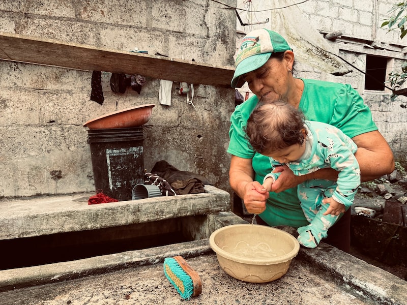 Una mujer de la comunidad de Sandomo lava las manos de un bebé con agua potable. Una mujer de la comunidad de Sandomo lava las manos de un bebé con agua potable.