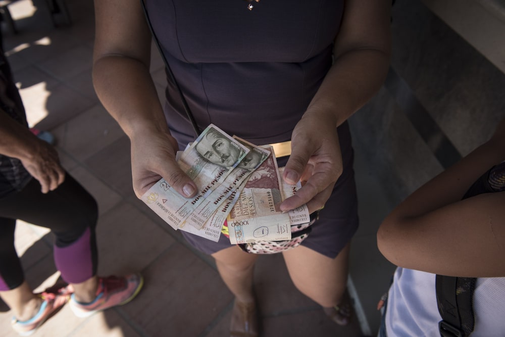 A woman receives Pesos in exchange for Bolivars after the re-opening of the borders in Cucuta, Colombia on Tuesday, Dec. 20, 2016. President Nicolas Maduro agreed to gradually re-open borders with Colombia after closing them last week in response to what officials called contraband "mafias." Photographer: Carlos Becerra/Bloomberg A woman receives Pesos in exchange for Bolivars after the re-opening of the borders in Cucuta, Colombia on Tuesday, Dec. 20, 2016. President Nicolas Maduro agreed to gradually re-open borders with Colombia after closing them last week in response to what officials called contraband "mafias." Photographer: Carlos Becerra/Bloomberg