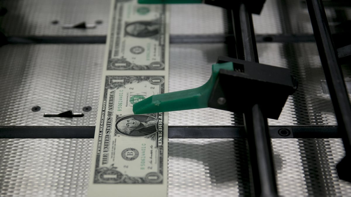 Tiras de billetes de un dólar pasan por una gran máquina de inspección y empaquetado mientras son cortadas en billetes individuales en la Oficina de Grabado e Impresión de EE. UU., en Washington D.C.