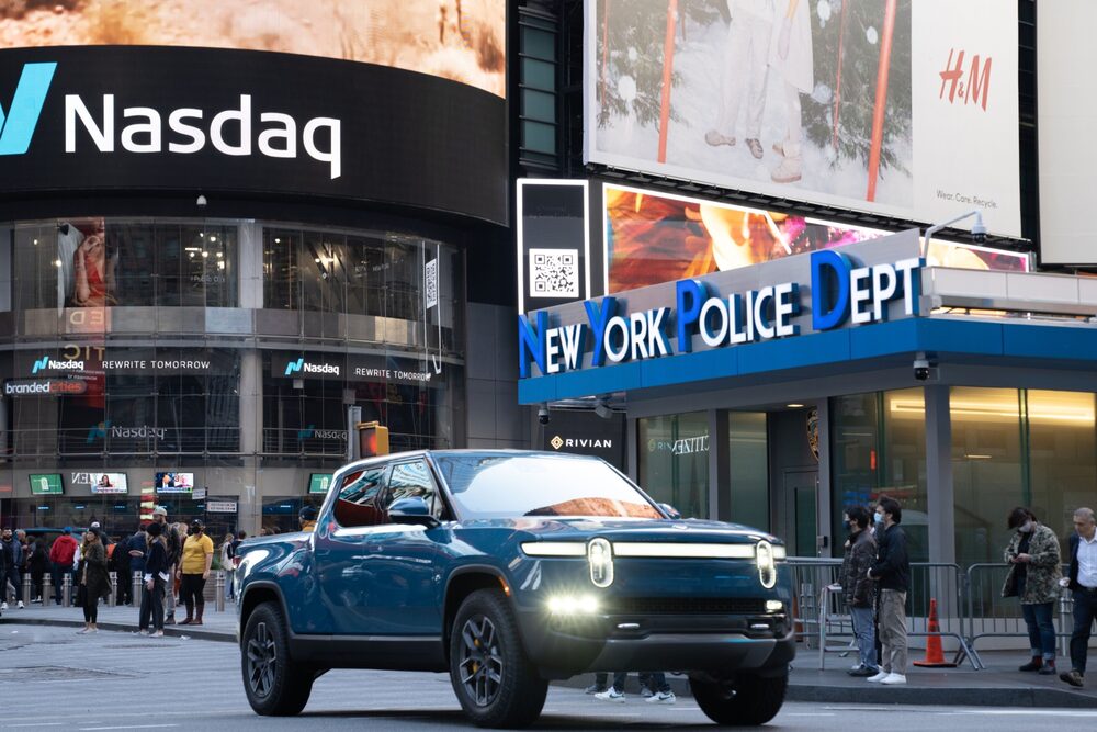 Picape elétrica da Rivian em frente ao painel eletrônico da Nasdaq na Times Square, em Nova York, no IPO da empresa em novembro de 2021 Picape elétrica da Rivian em frente ao painel eletrônico da Nasdaq na Times Square, em Nova York, no IPO da empresa em novembro de 2021