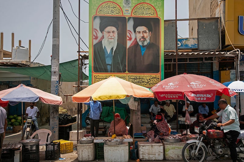 Vendedores ambulantes de comida sentados bajo carteles del antiguo líder supremo Ali Jamenei y del actual líder supremo Mojtaba Jamenei el 17 de mayo de 2026 a orillas del estrecho de Ormuz, en la isla de Qeshm, Irán. Vendedores ambulantes de comida sentados bajo carteles del antiguo líder supremo Ali Jamenei y del actual líder supremo Mojtaba Jamenei el 17 de mayo de 2026 a orillas del estrecho de Ormuz, en la isla de Qeshm, Irán.