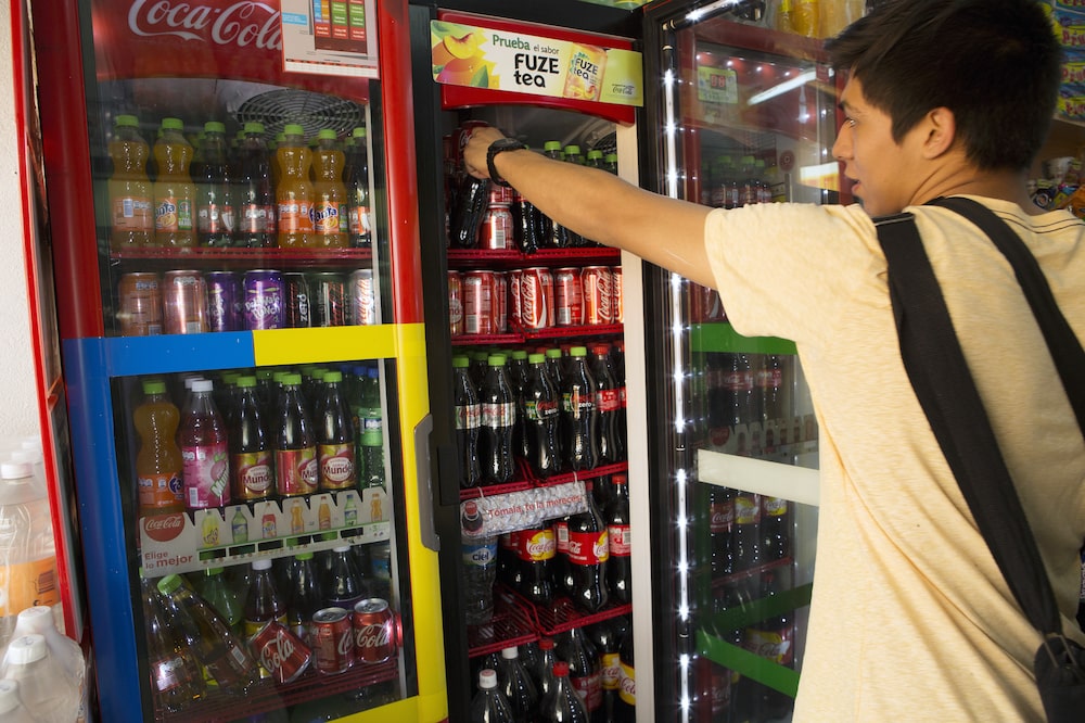 A customer reaches for a bottle of Coca-Cola Co. soda at a store in the Zona Rosa neighborhood of Mexico City, Mexico, on Wednesday, April 2, 2014. The world's biggest soft-drink guzzlers are taking smaller sips after Mexico raised taxes on sugary refreshments. Volumes of Sprite, Coke and other beverages may fall as much as 7 percent this year at Coca-Cola Femsa SAB, according to the company, which is passing the levy on to consumers with price increases. Photographer: Susana Gonzalez/Bloomberg A customer reaches for a bottle of Coca-Cola Co. soda at a store in the Zona Rosa neighborhood of Mexico City, Mexico, on Wednesday, April 2, 2014. The world's biggest soft-drink guzzlers are taking smaller sips after Mexico raised taxes on sugary refreshments. Volumes of Sprite, Coke and other beverages may fall as much as 7 percent this year at Coca-Cola Femsa SAB, according to the company, which is passing the levy on to consumers with price increases. Photographer: Susana Gonzalez/Bloomberg