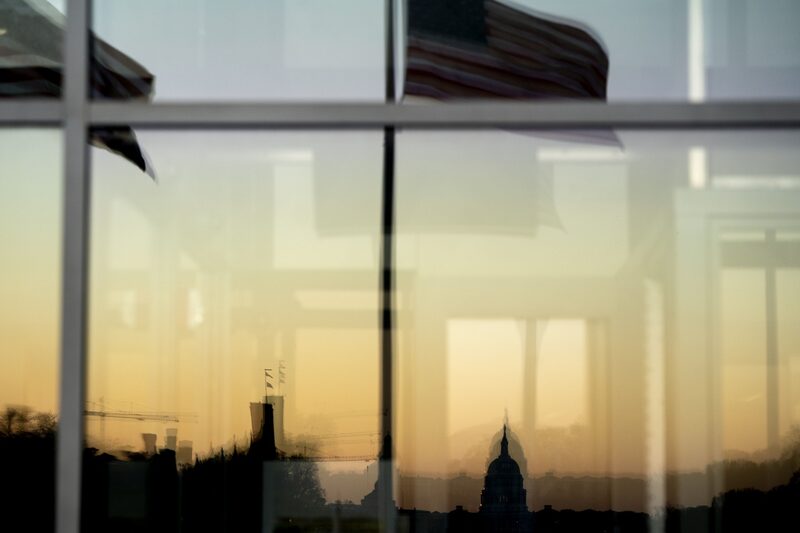 El edificio del Capitolio de EE.UU. y la bandera estadounidense reflejados en una ventana en Washington, D.C., EE.UU. El edificio del Capitolio de EE.UU. y la bandera estadounidense reflejados en una ventana en Washington, D.C., EE.UU.