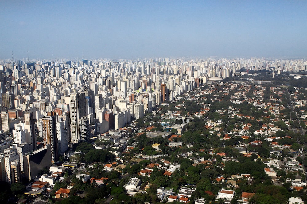 Vista aérea dos Jardins, em São Paulo: logo à esquerda, na faixa com prédios, está o Jardim Paulista e ruas como a Oscar Freire, valorizados pela oferta de lojas, restaurantes e cafés de alto padrão, ao mesmo tempo em que está próxima do bairro de casas do Jardim América (logo à direita) Vista aérea dos Jardins, em São Paulo: logo à esquerda, na faixa com prédios, está o Jardim Paulista e ruas como a Oscar Freire, valorizados pela oferta de lojas, restaurantes e cafés de alto padrão, ao mesmo tempo em que está próxima do bairro de casas do Jardim América (logo à direita)