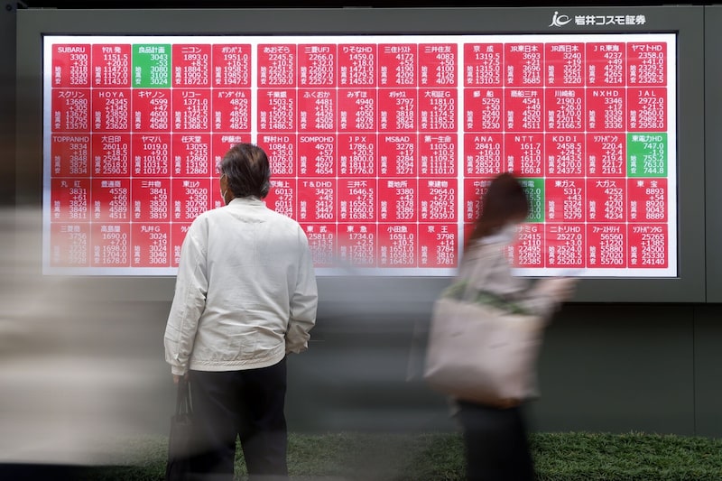 Una pantalla muestra el aumento de los precios de las acciones frente a una firma de valores en Tokio, Japón. Una pantalla muestra el aumento de los precios de las acciones frente a una firma de valores en Tokio, Japón.
