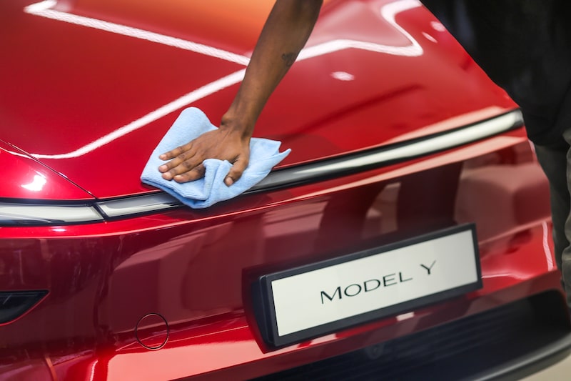 A worker cleans a Tesla Model Y electric vehicle. A worker cleans a Tesla Model Y electric vehicle.
