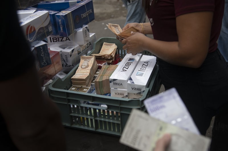 Billetes de dólares estadounidenses y bolívares en el barrio de Catia de Caracas, Venezuela. Billetes de dólares estadounidenses y bolívares en el barrio de Catia de Caracas, Venezuela.