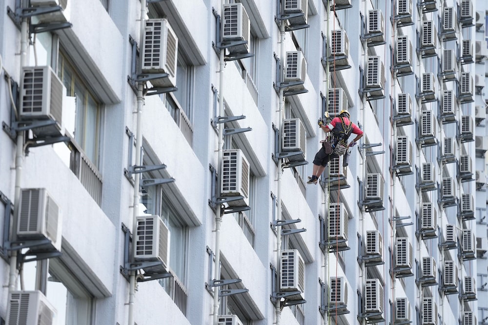 Um lavador de janelas cercado por unidades de ar-condicionado em um prédio de apartamentos em Tóquio em 21 de julho, quando as temperaturas na área subiram cerca de 9°C (16F) acima da média. Foto: Toru Hanai/Bloomberg Um lavador de janelas cercado por unidades de ar-condicionado em um prédio de apartamentos em Tóquio em 21 de julho, quando as temperaturas na área subiram cerca de 9°C (16F) acima da média. Foto: Toru Hanai/Bloomberg