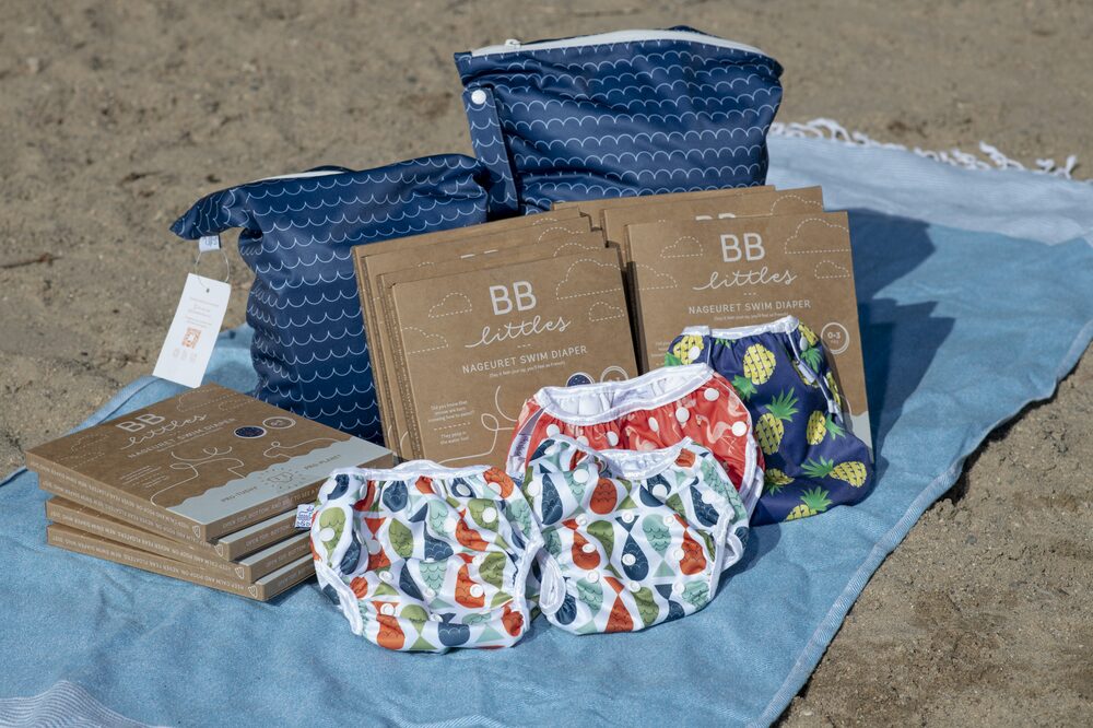 Foto de uma esteira na praia com algumas fraldas laváveis e embalagens de presente em cima Foto de uma esteira na praia com algumas fraldas laváveis e embalagens de presente em cima