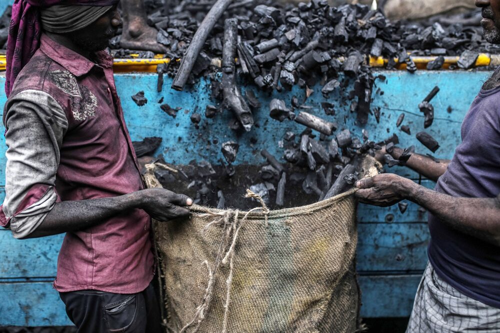 Trabajadores descargan un camión de carbón vegetal en un mercado mayorista de Mumbai, India. Trabajadores descargan un camión de carbón vegetal en un mercado mayorista de Mumbai, India.