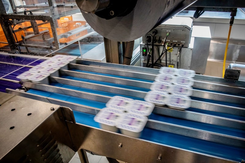 Los productos se transportan a lo largo de una cinta transportadora en una cooperativa lechera en España. Los productos se transportan a lo largo de una cinta transportadora en una cooperativa lechera en España.