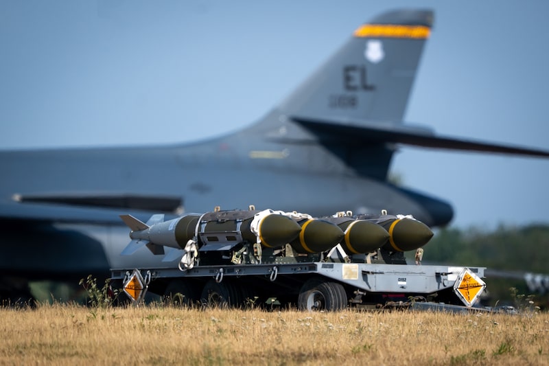 Municiones militares transportadas en una plataforma, con un avión de carga al fondo en una base aérea. Municiones militares transportadas en una plataforma, con un avión de carga al fondo en una base aérea.