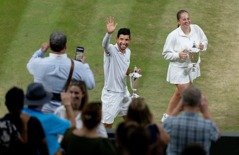 Marcelo Arévalo y Jelena Ostapenko, con el trofeo de dobles mixtos, saludan a los espectadores tras ganar su partido, celebrado en el All England Lawn Tennis Club, en Wimbledon, el 9 de julio de 2026. Marcelo Arévalo y Jelena Ostapenko, con el trofeo de dobles mixtos, saludan a los espectadores tras ganar su partido, celebrado en el All England Lawn Tennis Club, en Wimbledon, el 9 de julio de 2026.