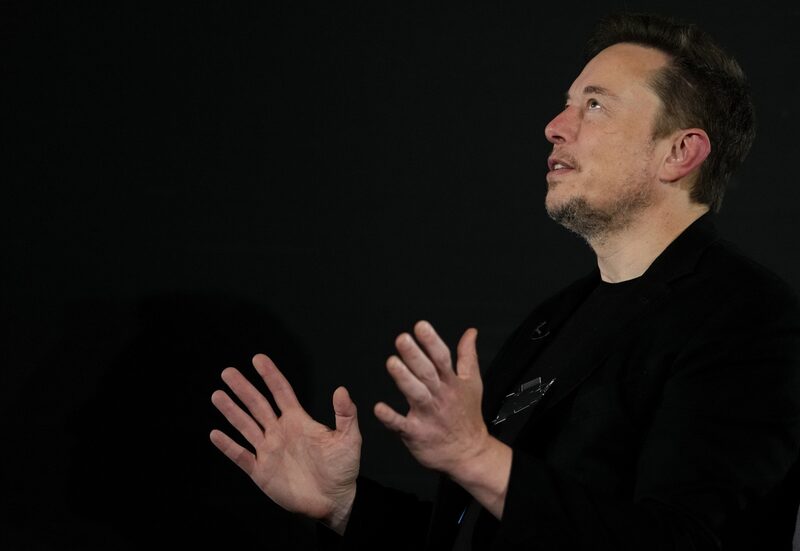 Elon Musk gesticulando, ele usa uma roupa preta de mangas longas Elon Musk gesticulando, ele usa uma roupa preta de mangas longas