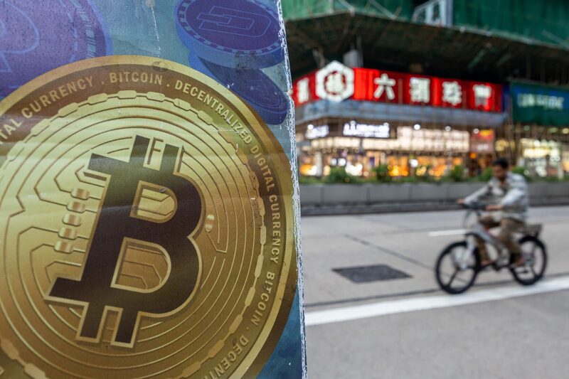 The Bitcoin logo in Hong Kong, China, on Tuesday, Dec. 5, 2023. Bitcoin shrugged off a dip in global stock markets to set another more than 19-month high, a sign of its decoupling from other assets. Photographer: Paul Yeung/Bloomberg The Bitcoin logo in Hong Kong, China, on Tuesday, Dec. 5, 2023. Bitcoin shrugged off a dip in global stock markets to set another more than 19-month high, a sign of its decoupling from other assets. Photographer: Paul Yeung/Bloomberg