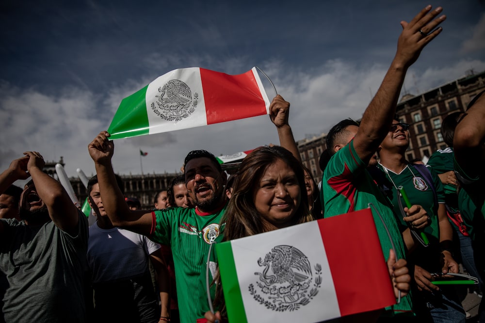 Soccer fans hold Mexican flags while watching a monitor broadcasting the Group F opening match of the FIFA World Cup between Mexico and Germany at a viewing party in the Zocalo in Mexico City, Mexico, on Sunday, June 17, 2018. Mexico's Hirving Lozano goal gave his team a 1-0 stunning victor over World Cup defending champions Germany. Photographer: Alejandro Cegarra/Bloomberg Soccer fans hold Mexican flags while watching a monitor broadcasting the Group F opening match of the FIFA World Cup between Mexico and Germany at a viewing party in the Zocalo in Mexico City, Mexico, on Sunday, June 17, 2018. Mexico's Hirving Lozano goal gave his team a 1-0 stunning victor over World Cup defending champions Germany. Photographer: Alejandro Cegarra/Bloomberg