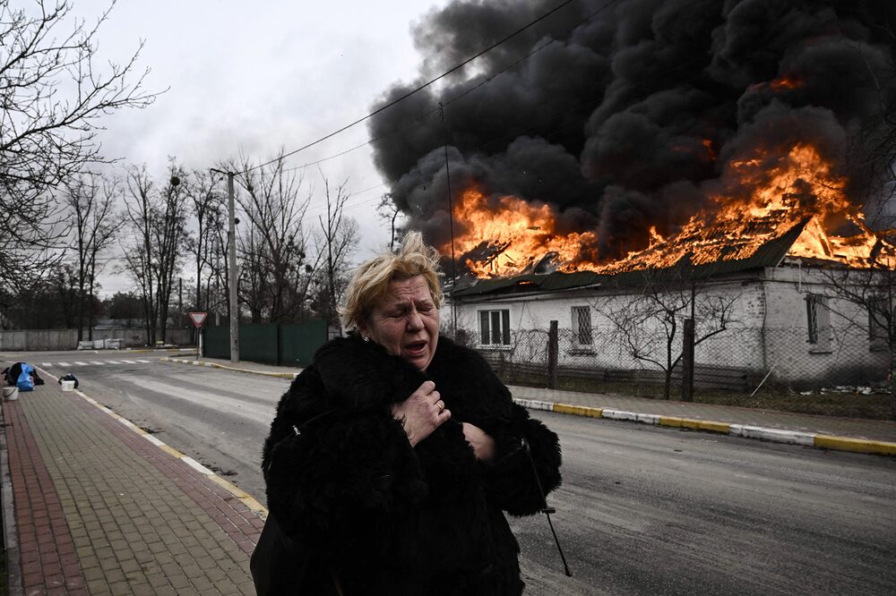 Uma mulher está perto de uma casa em chamas em Irpin, nos arredores de Kiev, em 4 de março.Fotógrafo: Aris Messinins/AFP/Getty Images Uma mulher está perto de uma casa em chamas em Irpin, nos arredores de Kiev, em 4 de março.Fotógrafo: Aris Messinins/AFP/Getty Images