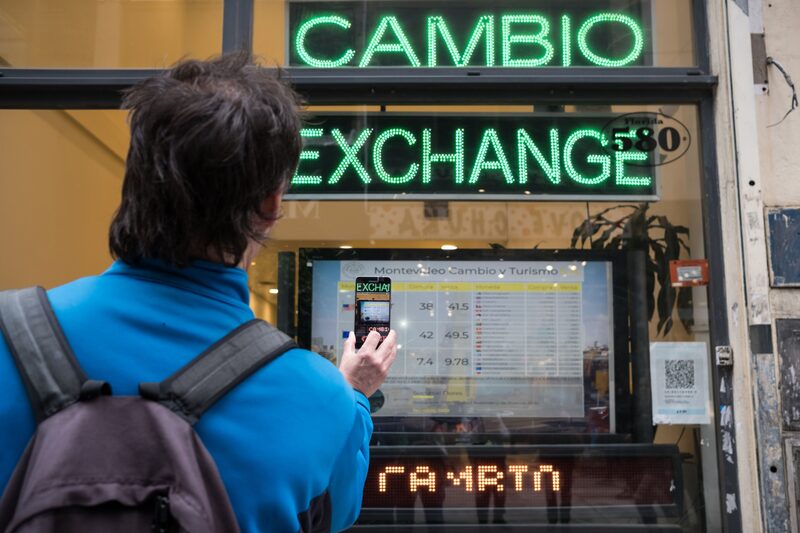 A pedestrian uses a mobile device to take a photograph of a sign displaying exchange rates outside of a currency exchange house in Buenos Aires, Argentina, on Thursday, Aug. 30, 2018. Argentina's currency crisis intensified on Thursday as the peso plunged 20 percent in a rout that only accelerated after the central bank tried to shore up confidence with an emergency increase in interest rates. Photographer: Erica Canepa/Bloomberg A pedestrian uses a mobile device to take a photograph of a sign displaying exchange rates outside of a currency exchange house in Buenos Aires, Argentina, on Thursday, Aug. 30, 2018. Argentina's currency crisis intensified on Thursday as the peso plunged 20 percent in a rout that only accelerated after the central bank tried to shore up confidence with an emergency increase in interest rates. Photographer: Erica Canepa/Bloomberg