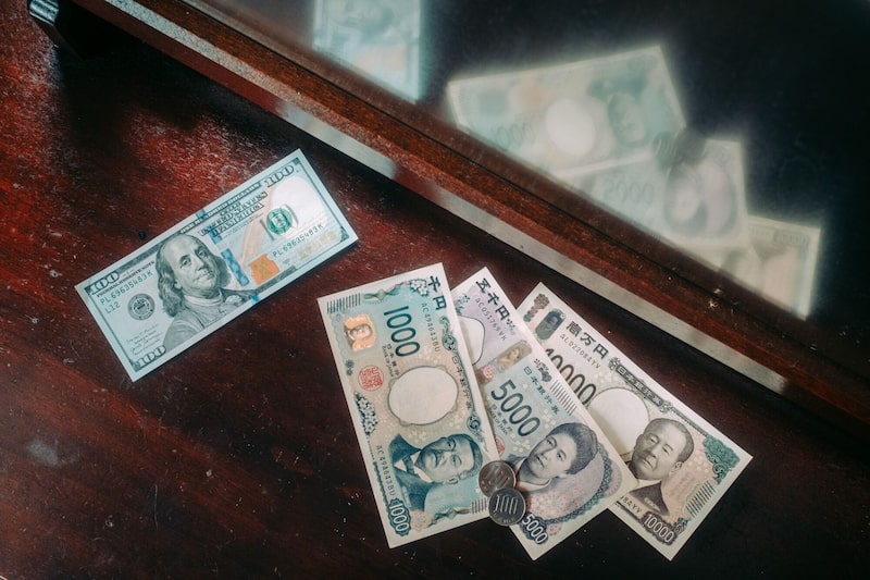Un billete de 100 dólares estadounidenses y billetes de yen japonés con monedas dispuestos en Kioto, Japón. Un billete de 100 dólares estadounidenses y billetes de yen japonés con monedas dispuestos en Kioto, Japón.