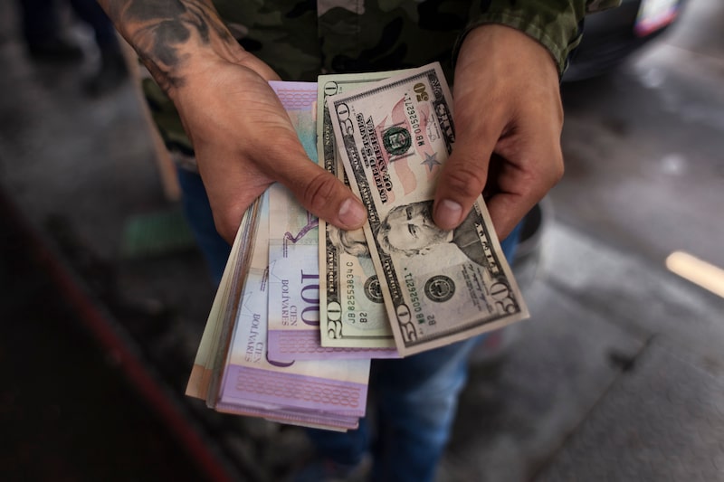 Una persona sostiene dólares y bolívares venezolanos para pagar gasolina en Caracas, Venezuela. Foto: Adriana Loureiro Fernández/Bloomberg. Una persona sostiene dólares y bolívares venezolanos para pagar gasolina en Caracas, Venezuela. Foto: Adriana Loureiro Fernández/Bloomberg.
