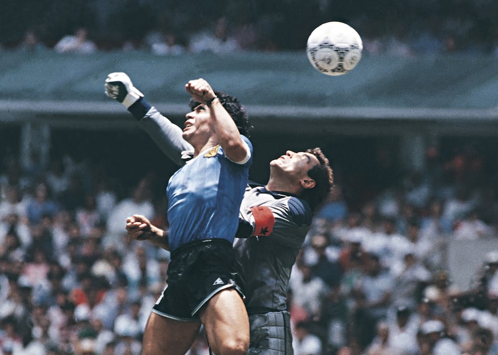 Diego Maradona, da Argentina, usa a mão para marcar o primeiro gol da equipe na partida das quartas de final da Copa do Mundo de 1986 contra a Inglaterra, na Cidade do México. Diego Maradona, da Argentina, usa a mão para marcar o primeiro gol da equipe na partida das quartas de final da Copa do Mundo de 1986 contra a Inglaterra, na Cidade do México.