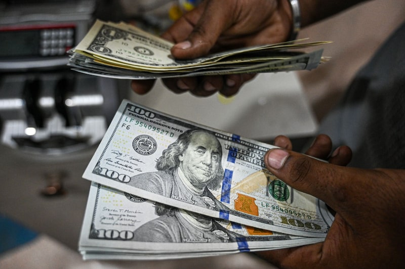 En la imagen, un empleado cuenta billetes de dólares estadounidenses en una casa de cambio. En la imagen, un empleado cuenta billetes de dólares estadounidenses en una casa de cambio.