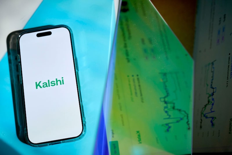La aplicación de Kalshi aparece en la pantalla de un teléfono móvil, junto a gráficos de mercados de predicción de la plataforma. La aplicación de Kalshi aparece en la pantalla de un teléfono móvil, junto a gráficos de mercados de predicción de la plataforma.