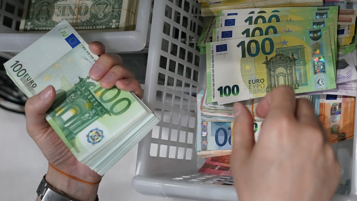 Un empleado sostiene un fajo de billetes de 100 euros en Ninja Money Exchange.