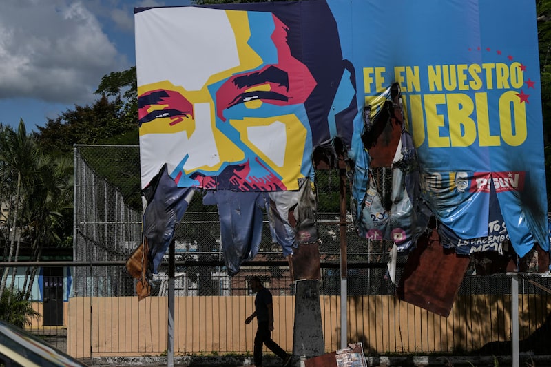 Um homem caminha sob um gigantesco outdoor com a imagem de Nicolás Maduro, que foi vandalizado durante fortes protestos contra o resultado da eleição presidencial no país, em Valencia, no estado de Carabobo, na Venezuela, em 31 de julho de 2024. (Photo by Yuri CORTEZ / AFP) (Photo by YURI CORTEZ/AFP via Getty Images) Um homem caminha sob um gigantesco outdoor com a imagem de Nicolás Maduro, que foi vandalizado durante fortes protestos contra o resultado da eleição presidencial no país, em Valencia, no estado de Carabobo, na Venezuela, em 31 de julho de 2024. (Photo by Yuri CORTEZ / AFP) (Photo by YURI CORTEZ/AFP via Getty Images)