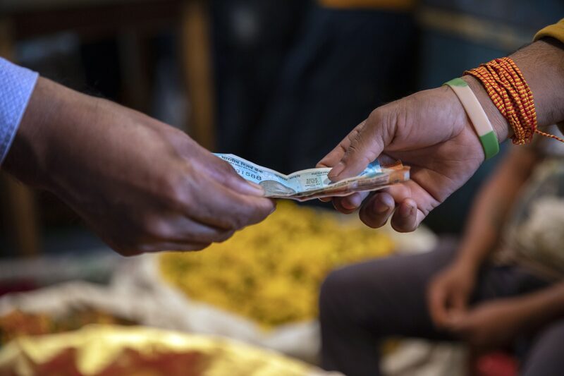 Una persona le da a otra un billete de dólar. Fotógrafo: Samyukta Lakshmi/Bloomberg. Una persona le da a otra un billete de dólar. Fotógrafo: Samyukta Lakshmi/Bloomberg.