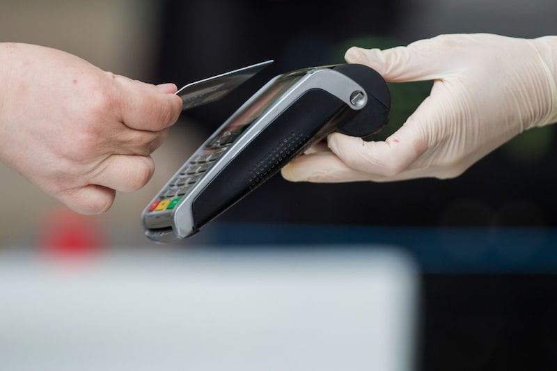 Un cliente utiliza una tarjeta bancaria para realizar un pago sin contacto en un puesto de mercado. Un cliente utiliza una tarjeta bancaria para realizar un pago sin contacto en un puesto de mercado.