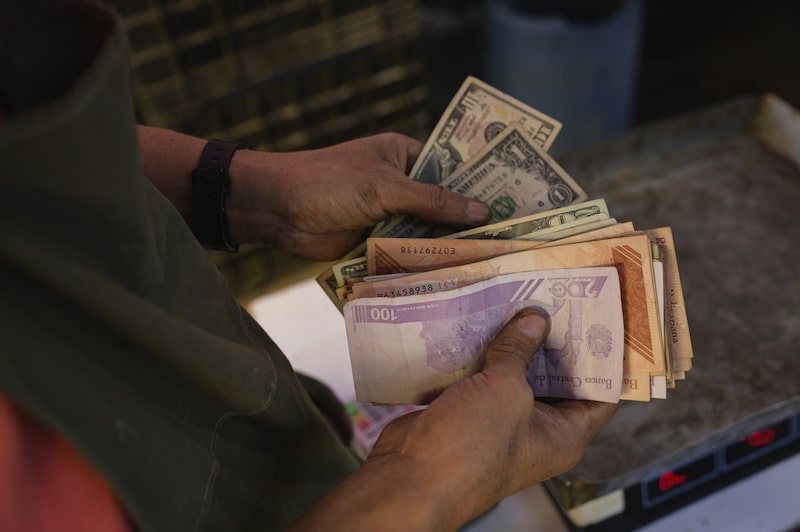 Un vendedor cuenta billetes de dólar y de bolívar en un mercado de Caracas.
Fuente: Bloomberg/Bloomberg
Un vendedor cuenta billetes de dólar y de bolívar en un mercado de Caracas.
Fuente: Bloomberg/Bloomberg